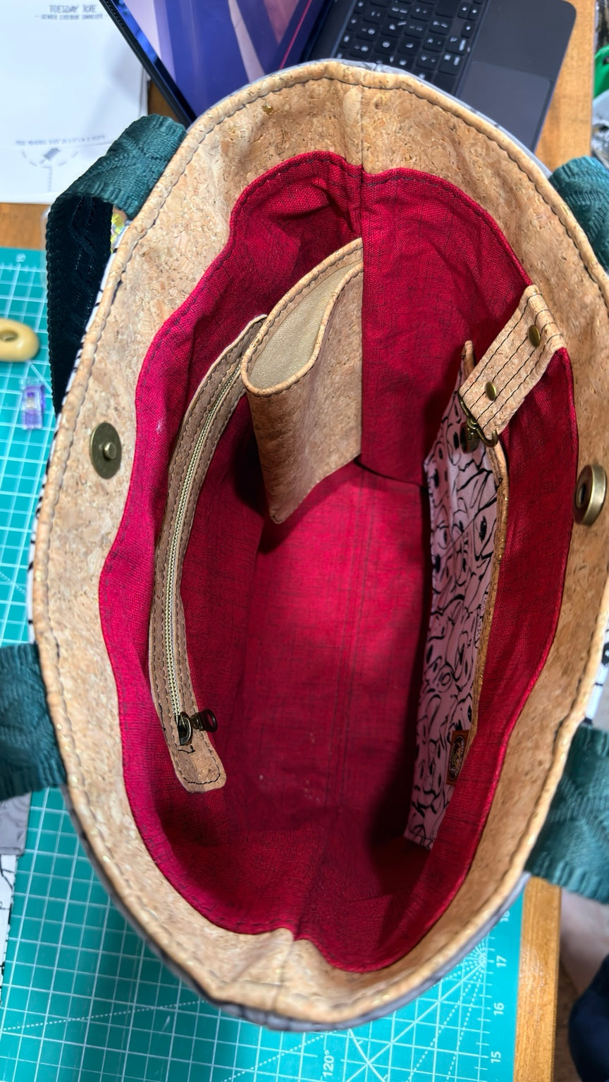 Overhead interior view of dog-print tote showing burgundy lining, cork trim, zipper pocket and hanging accessory pocket