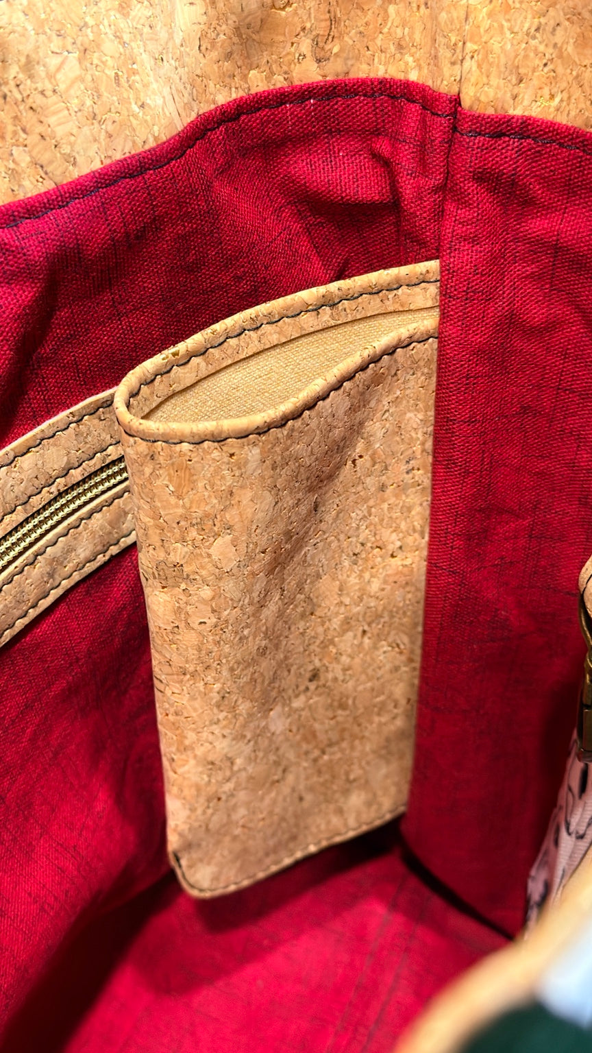 Close-up of cork-trimmed interior zipper pocket inside burgundy-lined dog-print tote